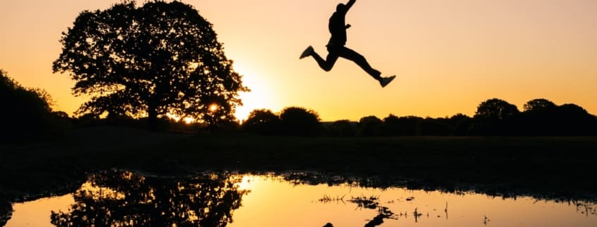 a person jumping in the air in front of a lake